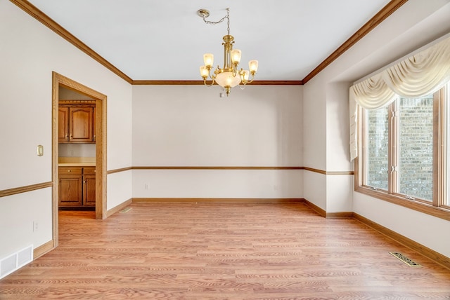 spare room featuring an inviting chandelier, light hardwood / wood-style floors, and crown molding