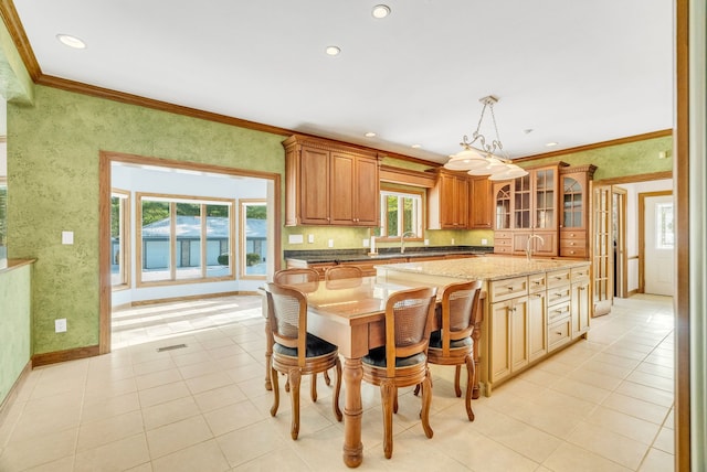 kitchen with hanging light fixtures, light tile patterned flooring, a center island, and crown molding