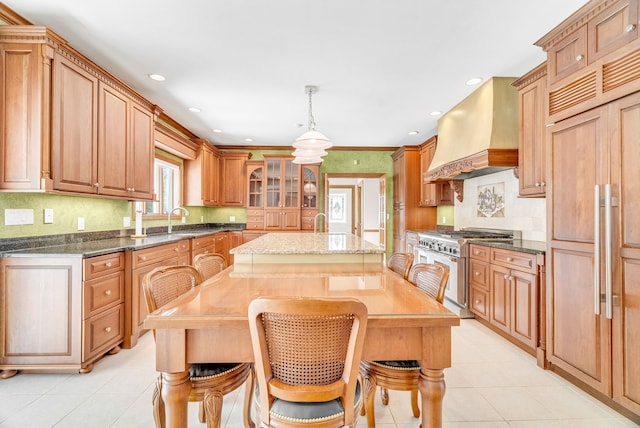 kitchen featuring a center island, custom exhaust hood, dark stone counters, high quality appliances, and pendant lighting