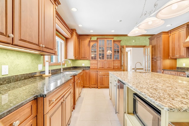 kitchen featuring decorative light fixtures, dark stone counters, and sink