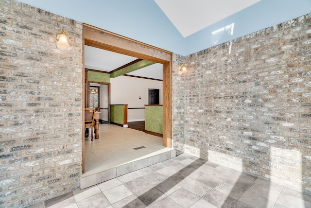 corridor featuring lofted ceiling, brick wall, and light tile patterned floors