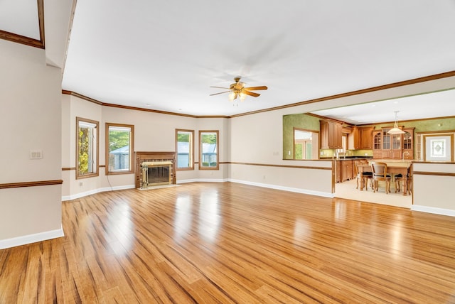 unfurnished living room featuring light wood-type flooring, ceiling fan, and crown molding