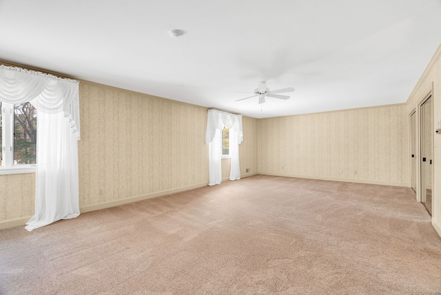 unfurnished room with ceiling fan, a wealth of natural light, and light carpet