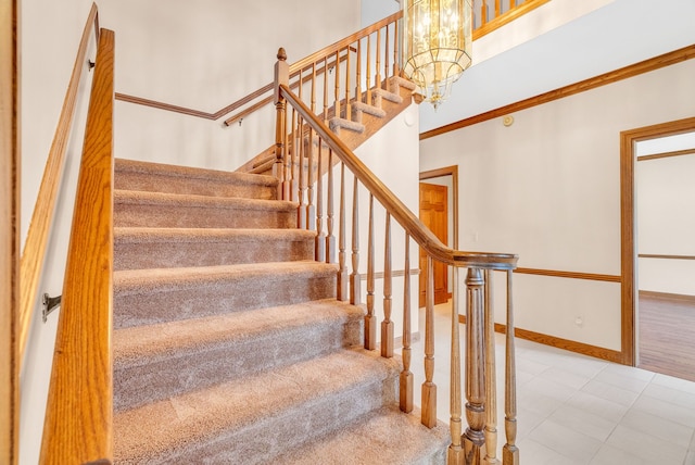 stairway with ornamental molding and a notable chandelier