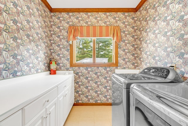 laundry area featuring ornamental molding, cabinets, washer and clothes dryer, and light tile patterned floors