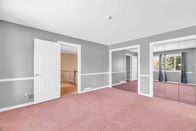 unfurnished bedroom with two closets and carpet