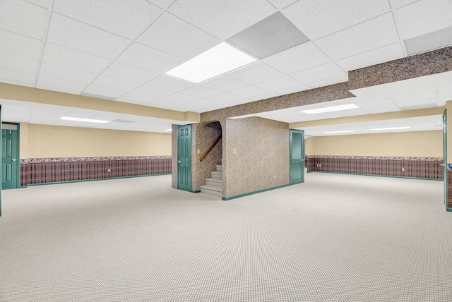 basement featuring a paneled ceiling and carpet flooring