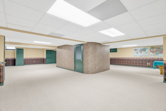 basement with a paneled ceiling and carpet floors