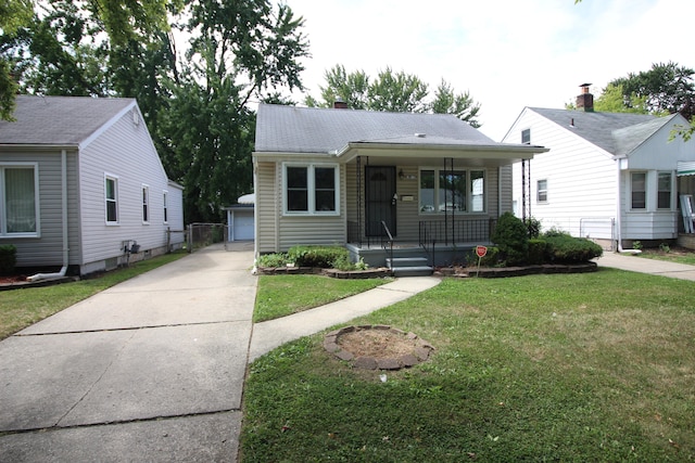 bungalow featuring a garage, a front lawn, and an outdoor structure