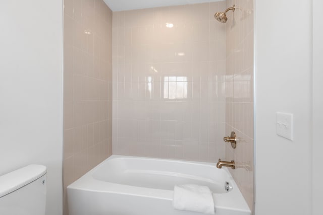 bathroom featuring toilet and tiled shower / bath