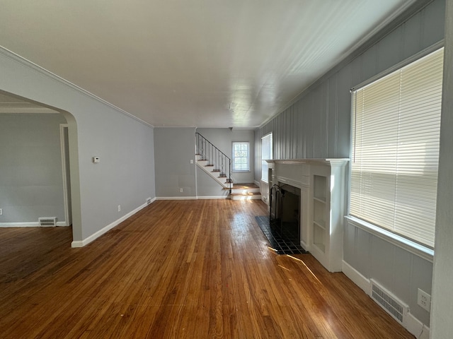 unfurnished living room featuring hardwood / wood-style floors, ornamental molding, and a fireplace