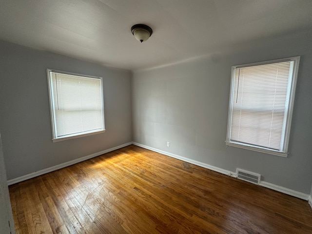 empty room with a healthy amount of sunlight and hardwood / wood-style flooring