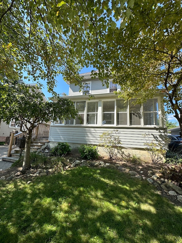 view of home's exterior with a lawn and a sunroom