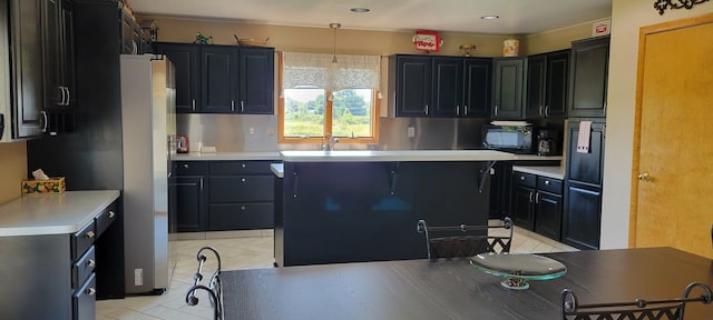 kitchen with decorative light fixtures, stainless steel refrigerator, and sink