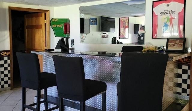 bar featuring a paneled ceiling and light tile patterned floors