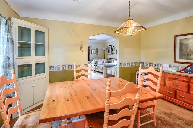 carpeted dining room featuring a notable chandelier