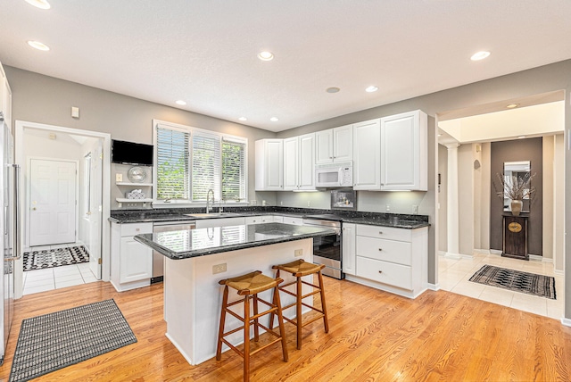 kitchen featuring sink, a kitchen island, white cabinetry, and appliances with stainless steel finishes