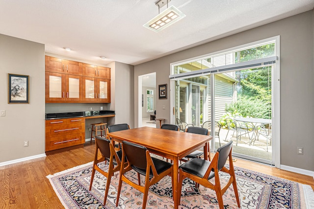 dining area featuring light wood-type flooring and a textured ceiling