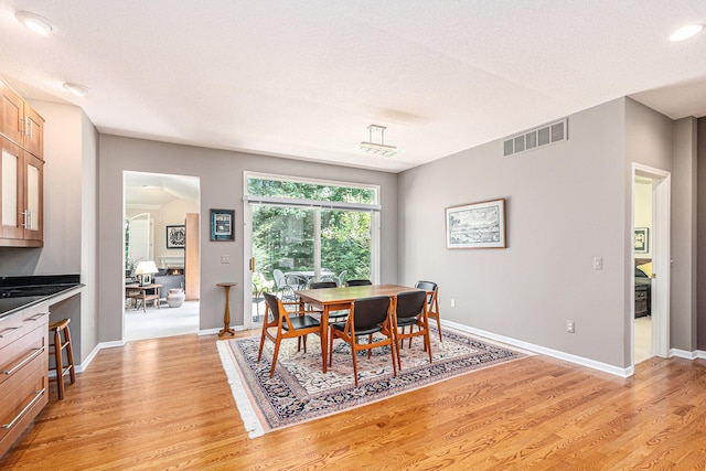 dining area featuring a textured ceiling and light hardwood / wood-style flooring