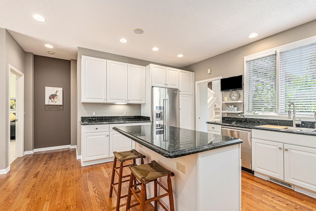 kitchen with sink, white cabinets, stainless steel appliances, and a kitchen island