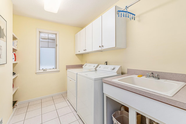 clothes washing area with sink, light tile patterned floors, cabinets, and washer and dryer