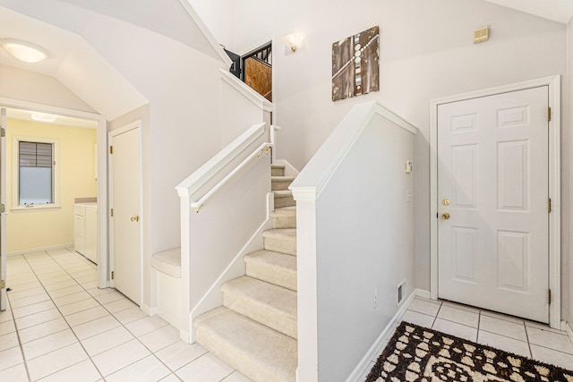 stairs with independent washer and dryer, tile patterned flooring, and vaulted ceiling