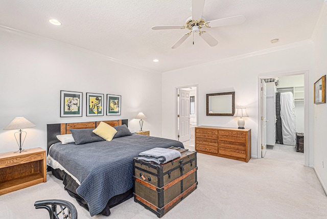 bedroom with crown molding, ceiling fan, light colored carpet, a walk in closet, and a closet