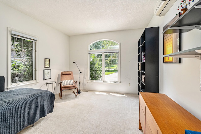 bedroom with a textured ceiling, a wall mounted AC, and light colored carpet