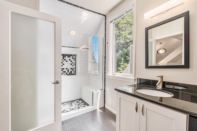 bathroom with tile patterned floors, vanity, a tile shower, and vaulted ceiling