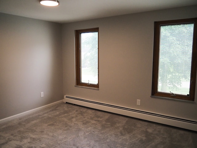 carpeted spare room with baseboard heating and a wealth of natural light