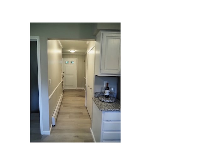 kitchen with light stone counters, light hardwood / wood-style flooring, white cabinets, and a baseboard heating unit