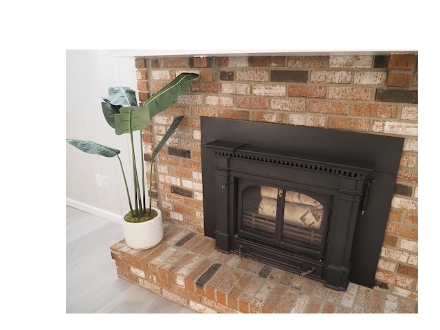 interior details featuring wood-type flooring and a brick fireplace