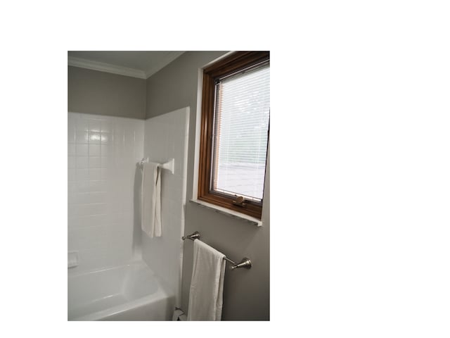 bathroom with tiled shower / bath combo and crown molding