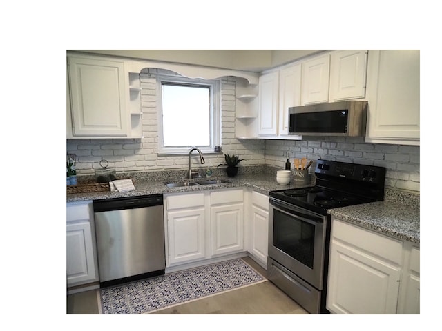 kitchen featuring dark stone counters, white cabinetry, sink, and stainless steel appliances