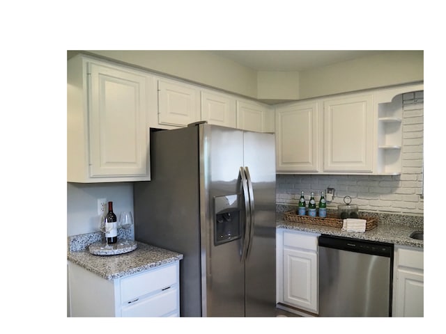 kitchen with light stone countertops, decorative backsplash, stainless steel appliances, and white cabinetry