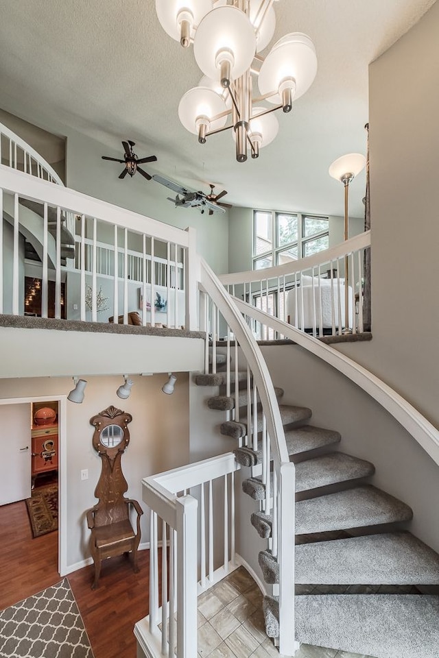 stairway featuring a textured ceiling, lofted ceiling, hardwood / wood-style floors, and ceiling fan with notable chandelier