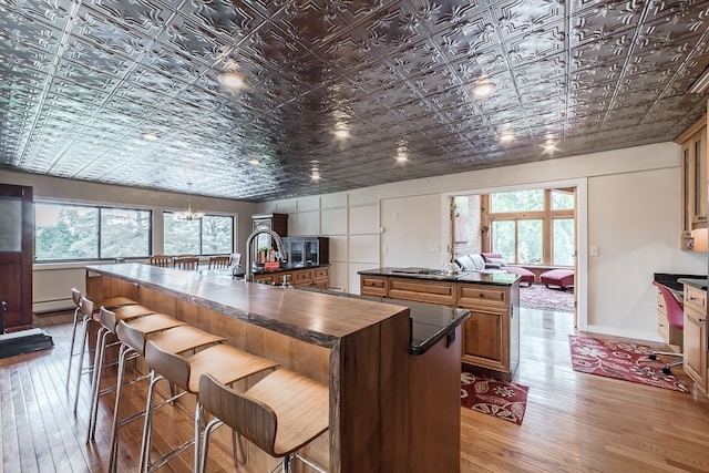 kitchen with a breakfast bar, an island with sink, a healthy amount of sunlight, and hardwood / wood-style flooring