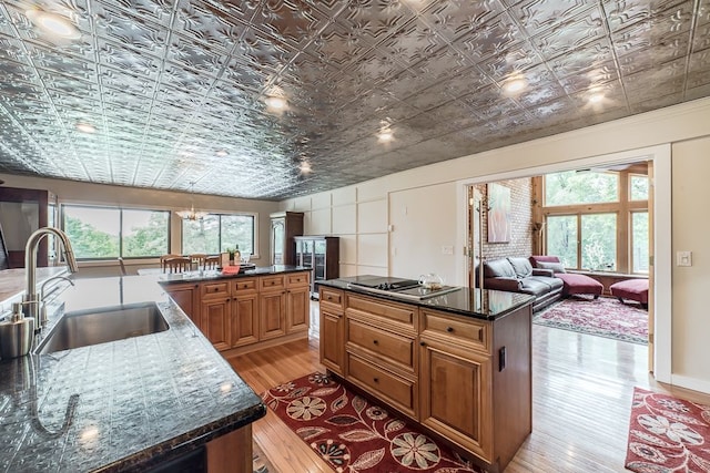 kitchen with a kitchen island with sink, sink, light hardwood / wood-style flooring, and stainless steel gas cooktop