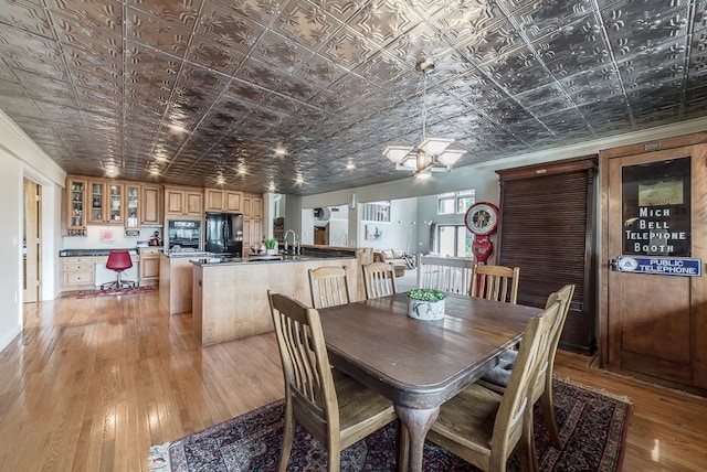 dining room featuring light wood-type flooring, a notable chandelier, and sink