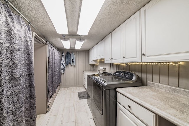 laundry room featuring cabinets, a textured ceiling, and washing machine and clothes dryer