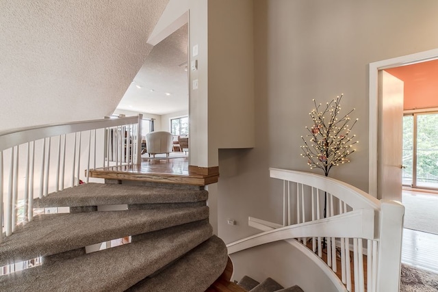 staircase with a textured ceiling and lofted ceiling