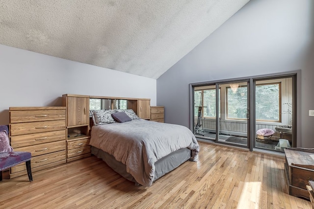 bedroom with access to exterior, light wood-type flooring, a textured ceiling, and high vaulted ceiling