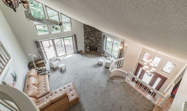 carpeted living room featuring a fireplace, a chandelier, high vaulted ceiling, and a healthy amount of sunlight