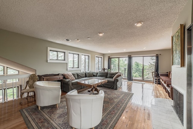 living room featuring a tile fireplace, wood-type flooring, and a textured ceiling