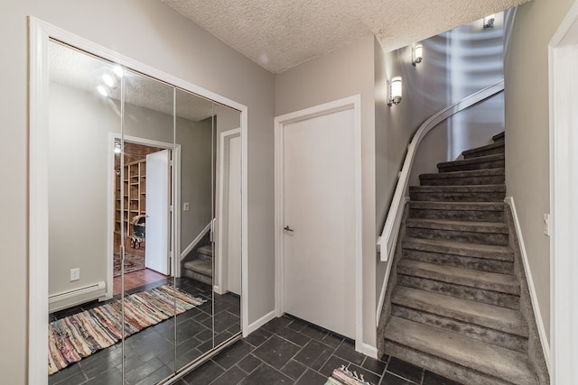 stairway with a textured ceiling and a baseboard heating unit