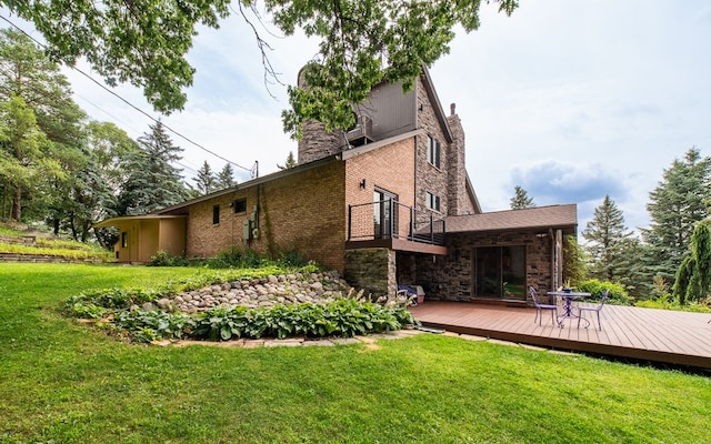 back of property with a balcony, a deck, and a yard