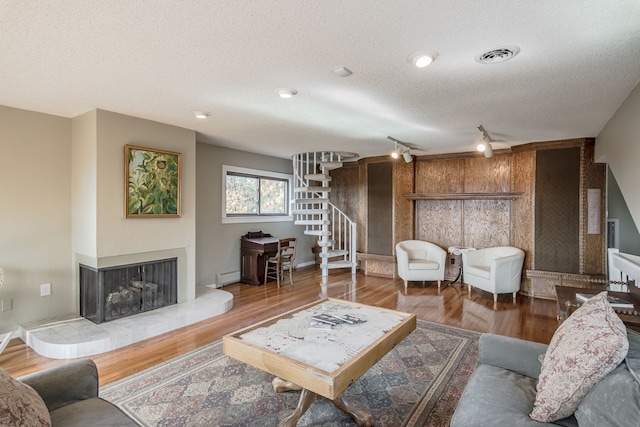 living room with wood-type flooring, a textured ceiling, and a baseboard radiator