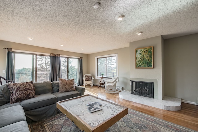 living room with hardwood / wood-style floors, a fireplace, and a textured ceiling