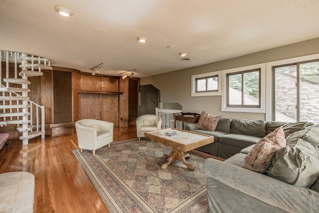 living room with wood walls, a healthy amount of sunlight, a textured ceiling, and wood-type flooring