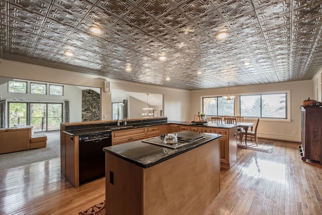 kitchen with dishwasher, kitchen peninsula, plenty of natural light, and light hardwood / wood-style floors